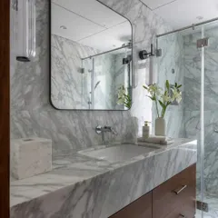 Another bathroom from the Parishram project, showcasing a beautiful grey marble. The custom wooden vanity adds warmth to the space, while the mirrored cabinet provides discreet storage.