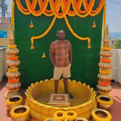 Another Haldi setup on a rooftop. The decor includes a green backdrop with marigold garlands and brass pots, creating a perfect photo opportunity.