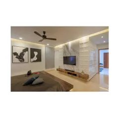 The master bedroom in Athulyam is a composition of simple forms and elegant materials. A floating bed and a low-profile media unit keep the space feeling open, while a textured partition wall adds visual interest and separates the sleeping area from the ensuite.
