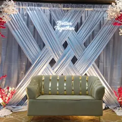 A modern engagement backdrop with crisscross silver drapes and arches of red and white flowers. The "Better Together" neon sign adds a trendy, personal touch to the stage.