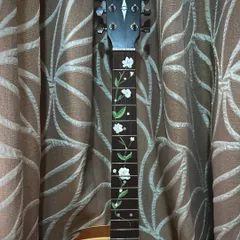 A full view of the painted guitar neck. The white flowers and green leaves create a beautiful contrast against the dark wood of the fretboard.