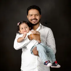 A father holds his child close, both sharing a sweet smile for the camera. This simple, classic portrait captures the strong and gentle bond between them.
