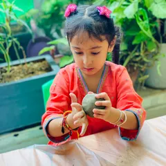 A young artist carefully shaping her Ganesha idol. Working with clay is a wonderful sensory experience that helps build hand strength and coordination.