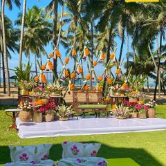 A fusion Haldi ceremony with a Malabari twist. This beachside setup features a backdrop of bamboo and marigolds, surrounded by colorful floral arrangements in earthen pots, blending tradition with a relaxed coastal vibe.