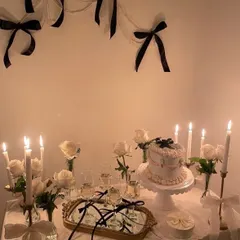 A chic and sophisticated dessert table setup with a black and white theme. We used white roses, elegant candles, a mirrored gold tray, and delicate black ribbon details to create a timeless and stylish look.