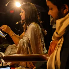 A beautiful, moody shot from our live music show. The artist is seen here with her harmonium, bathed in warm stage light, creating a serene and captivating atmosphere for the performance.