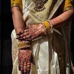 A stunning photo of a bride in a traditional South Indian saree, showcasing her beautifully stained mehendi. The dark henna provides a gorgeous contrast against her elegant attire.