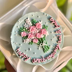 Celebrating love, one bite at a time. This adorable anniversary bento cake features a hand-piped frosting bouquet on a soft blue background, perfect for marking special moments.