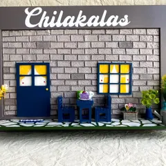 I designed this miniature nameplate for the 'Chilakalas' family, featuring a cozy outdoor scene. The design includes a hand-textured brick wall, a miniature door and window with curtains, and tiny furniture.