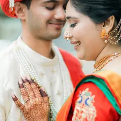 A close-up shot highlighting the bride's hand with an 'N' initial in her mehndi, resting gently on the groom's chest. A sweet, personal detail.