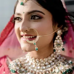 A close-up of the bride's joyful expression, highlighting her stunning polki nath and matching jewellery set. These detail shots preserve the memory of the carefully chosen bridal accessories.