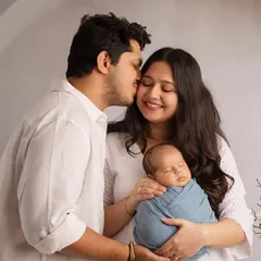 A father's gentle kiss for the mother of his child, as she holds their sleeping newborn. This is a story of love and new beginnings, captured with a soft, romantic feel.