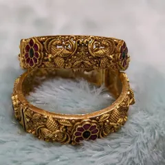 A pair of antique-finish bridal bangles (kadas) with Jadau stones and intricate peacock carvings. I offer these complimentary when you book a full bridal set!