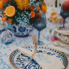 A beautiful tablescape featuring blue and white patterned plates, complemented by vibrant orange florals. This unexpected color combination creates a fresh and stylish look.