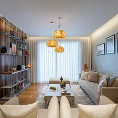 This living room showcases a harmonious blend of textures, from the fluted wood wall panels to the soft, earthy tones of the furnishings. Pendant lights made from banana fiber cast a warm, inviting glow over the space.