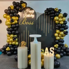A premium black and gold birthday setup for a boss in an office setting, featuring a custom backdrop and a balloon arch.