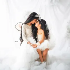 A magical moment between sisters in my dreamy clouds setup. Dressed as angels with crowns and wings, they share a sweet, gentle touch in this ethereal portrait.