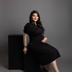 A modern and chic pose using simple black blocks as props. This minimalist setup keeps all the attention on the mom-to-be's confident smile and her lovely baby bump.