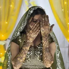 A beautiful bride showcasing her full-arm Dubai-style mehendi. The design is characterized by its flowing patterns and mix of bold and fine lines.