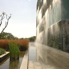 An integrated misting and irrigation system maintains the lushness of the KMC Headquarters' living facade. This image captures the system in action, a key component of the building's climate-responsive and sustainable design.