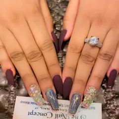 This set combines different textures for a dramatic effect. It features long, coffin-shaped nails in matte burgundy, with accent nails fully covered in holographic chrome and multi-colored crystals.