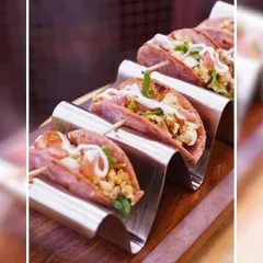 A close-up of our delicious mini tacos, filled with paneer and fresh toppings, and drizzled with a creamy sauce. They are served in a modern metal rack for a stylish presentation.