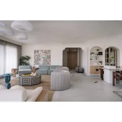 The main living area is a study in color, texture, and form. A powder blue sofa, lilac armchairs, and a custom painting referencing the family's travels create a space that is vibrant and full of life.