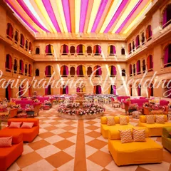 Vibrant Mehendi decor in a stunning palace courtyard. We used hues of orange, yellow, and pink to complement the venue's architecture and create a festive, royal atmosphere.