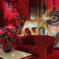 Every detail was chosen to build a narrative. A life-sized leopard figure stands proudly beside a velvet lounge setting, set against a wall of red florals, creating layers of texture and intrigue.