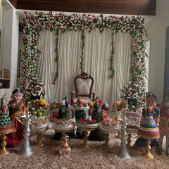 A beautiful and compact stage setup for a home engagement. A full floral arch of red and white roses frames a traditional throne, with an elegant offering table in the foreground.