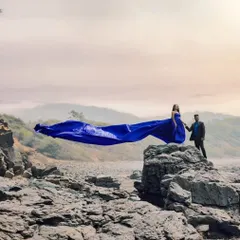 The royal blue gown stands out against the rugged, rocky landscape. This is a perfect choice for couples who want a bold color for their adventure pre-wedding session.