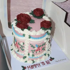Celebrating a "Mommy to be" with this gorgeous vintage-style cake. It features detailed floral piping in soft colors, elegant swag details, and deep red sugar roses on top.