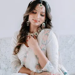 A close-up of the bride, her hand gently touching her necklace, showcasing the intricate details of the jewellery and her beautiful henna.