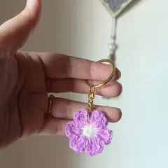 A single lilac floral keychain with a white center. The soft pastel color makes it a very sweet and gentle accessory.