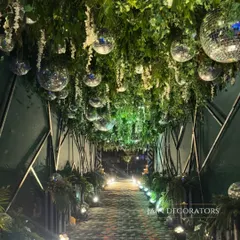 An entrance that promises a party. I created this tunnel of light and greenery, with a ceiling of hanging disco balls, to build excitement and lead guests into a glamorous sangeet night.