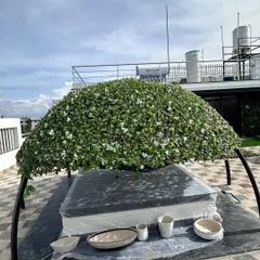 Another angle of the rooftop gazebo during installation. You can see the sturdy frame and the dense application of the artificial foliage, designed to withstand outdoor conditions.