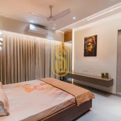 A floating console table in this bedroom serves as a minimalist TV unit, with a serene Buddha artwork above it. The backlighting behind the curtains adds a soft, ambient glow to the space.