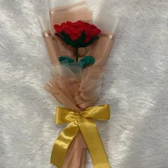 A cute, custom-made single rose bouquet. The classic red rose is wrapped in delicate pink and white paper with a gold ribbon, making it an elegant and timeless small gift.