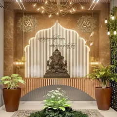 A grand and divine pooja space with a large Ganesha idol as the centerpiece. The arched backdrop with fluted panels and warm backlighting creates a serene and temple-like ambiance.