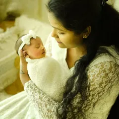 The look of love in a mother's eyes. Dressed in white lace, this mumma holds her sleeping baby, creating a soft and serene portrait of their new bond.