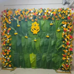 For this baby shower, I created a beautiful backdrop using a combination of banana leaves and a frame of colorful flowers. The Ganesha made of yellow flowers adds a lovely traditional touch.