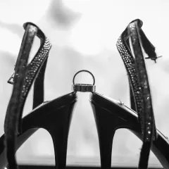 An artistic black and white shot of the wedding ring balanced perfectly between the bride's heels. It's a stylish and creative way to photograph the wedding details.