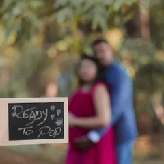A creative use of depth of field, this photo puts the fun "Ready to Pop" sign in sharp focus while the happy couple is blurred lovingly in the background.