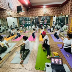 A view of our hybrid class setup, with students in seated twists both on their mats in the studio and on the screen from their homes.