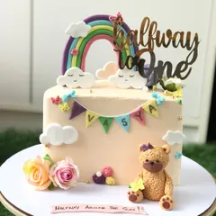 A "Halfway to One" cake for a six-month celebration. This design features a cute teddy bear, a pastel rainbow, and a little name banner.