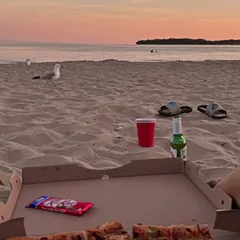 The perfect beach day setup: pizza, snacks, and a beautiful sunset over the water.