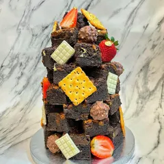 This is my signature Lotus Biscoff brownie stack, a unique alternative to a traditional birthday cake. It's a tower of rich, fudgy brownies decorated with fresh strawberries, white chocolate, and crunchy biscuits, perfect for any brownie lover.
