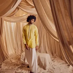 A full-length shot of a groom in traditional attire. The makeup and grooming are subtle, enhancing his natural features and ensuring he looks sharp and well-presented for his wedding ceremonies.