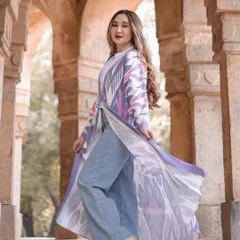 A full-length shot in the same arched corridor, showcasing how the model's modern outfit, with its flowing jacket, contrasts beautifully with the ancient stone pillars.