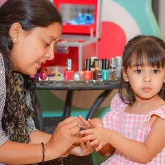 A little girl gets a fun and colorful manicure from one of our staff members during a spa party.